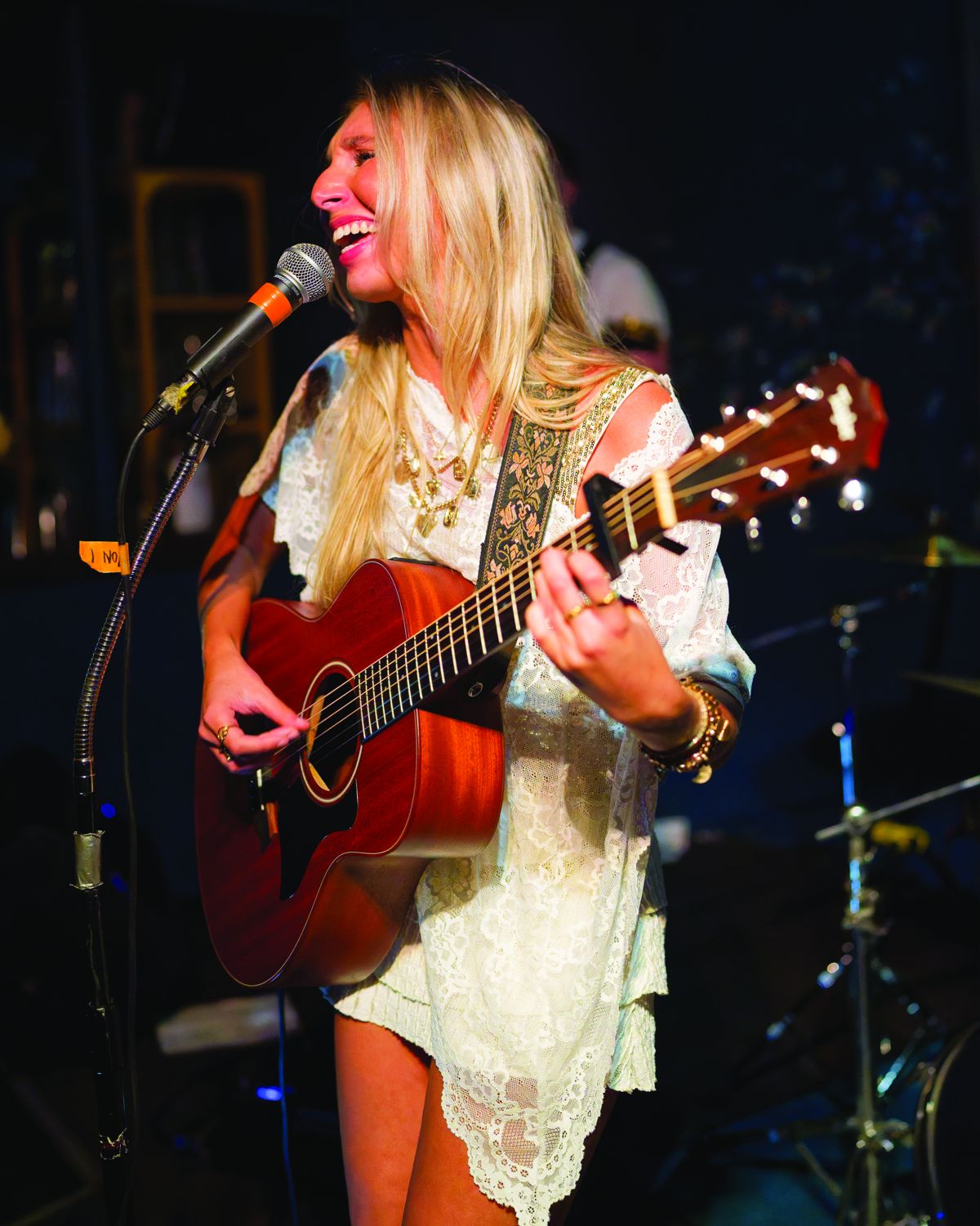 Sylvie laughing at the microphone with her acoustic guitar
